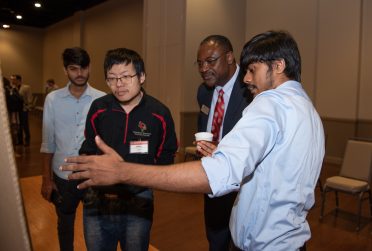 Dr. Aondover Tarhule, ice president for Academic Affairs and provost at Illinois State (second, right), meets with students presenting at the 2022 University Research Symposium.