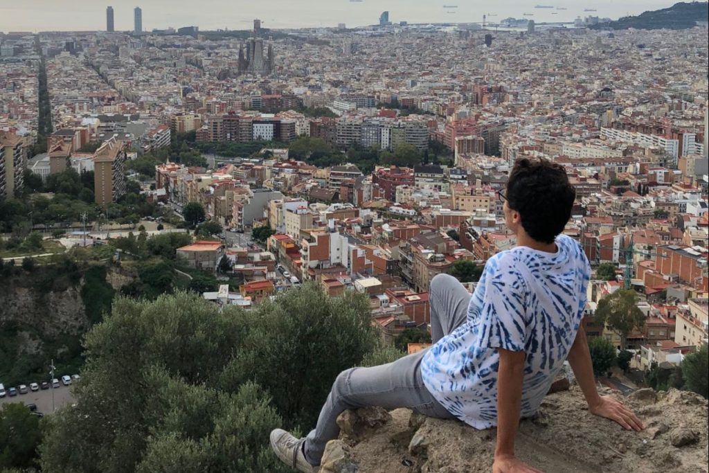 Student sitting on stone ledge, overlooking old italian city in distance.