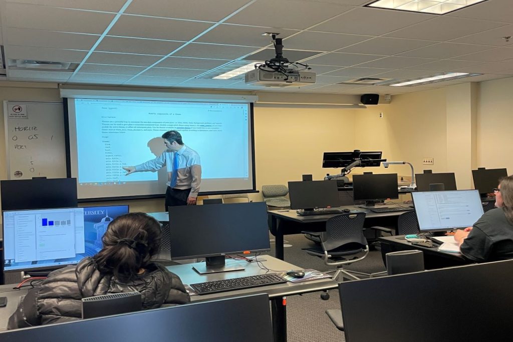 Professor at front of classroom pointing to screen